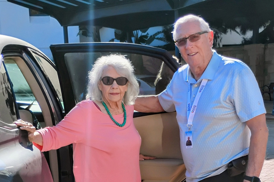 man and woman standing by a car smiling