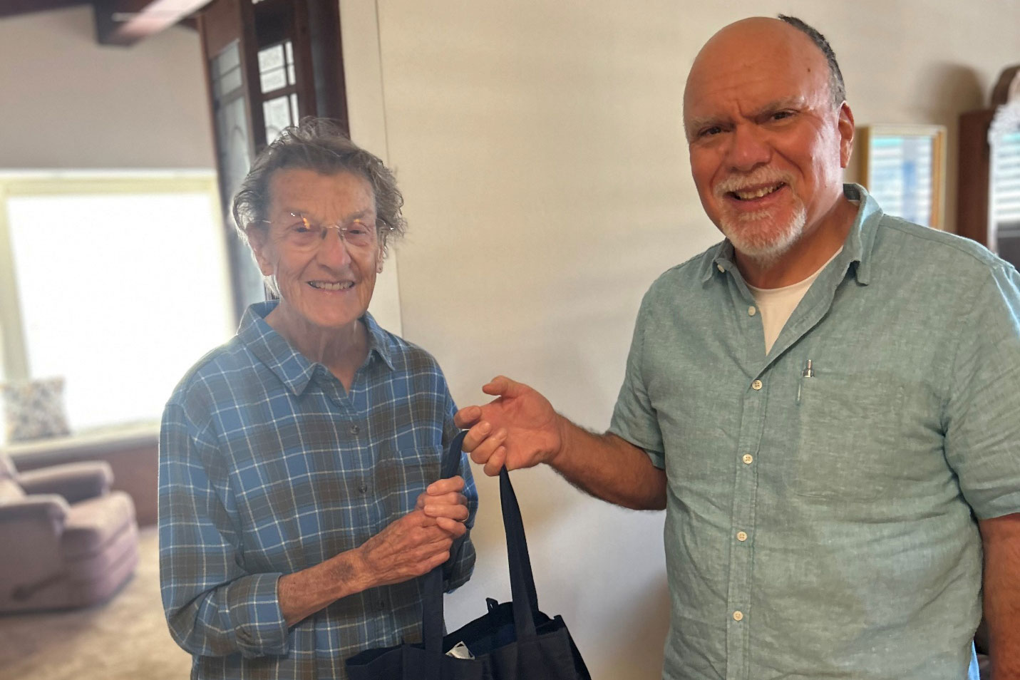 Man hands older woman a bag of food