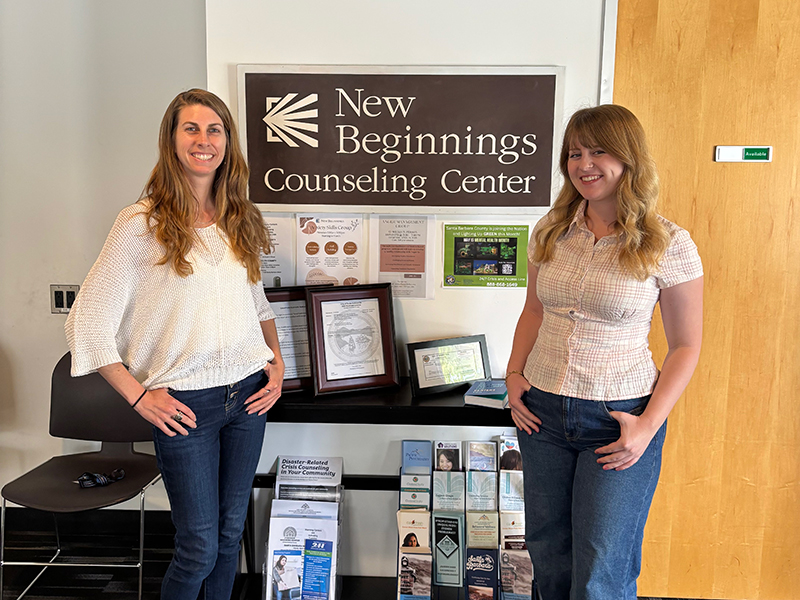 Two young, female counselors in front of the New Beginnings sign