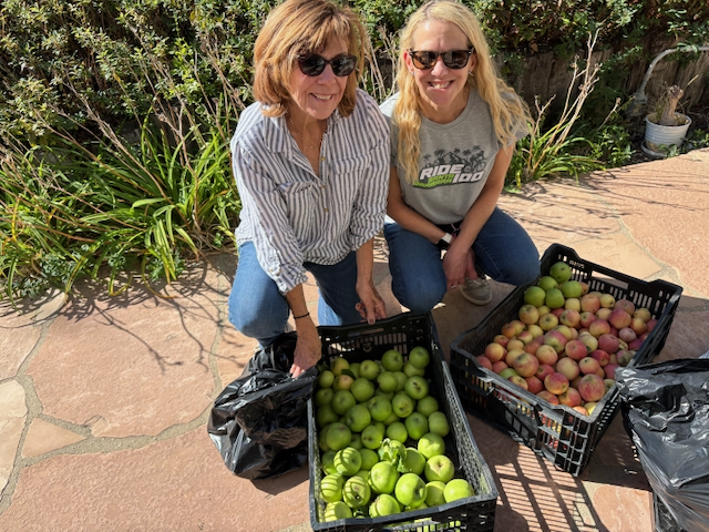 Two women smiling with boxes of fruits and vegetables