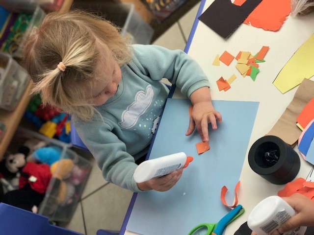 Little girl in blue playing with glue