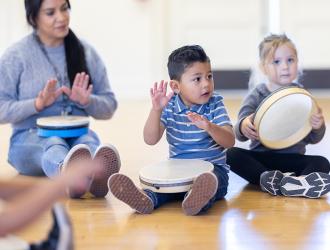 young children playing musical instruments with teacher