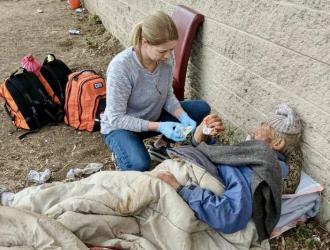 Doctors Without Walls volunteer assists homeless man