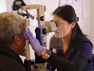 Optometrist using equipment to examine eyes of man