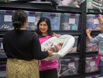 Volunteer handing baby items to woman