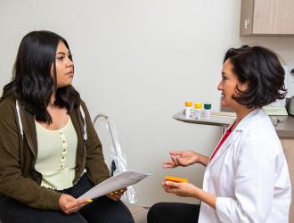 Woman in lab coat talking with female patient